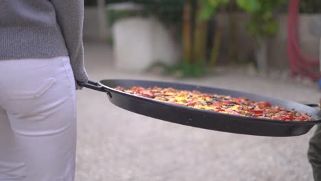 carrying paella to a gathering of people celebrating