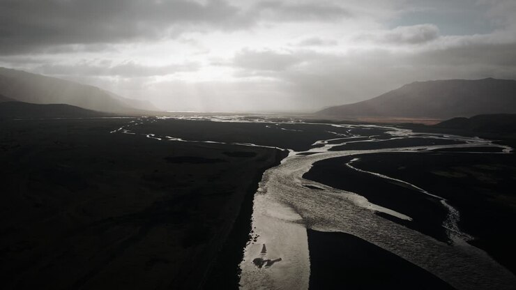 Cinematic aerial thor valley, glacial rivers flowing through black volcanic floodplain, thorsmörk dramatic moody landscape Iceland