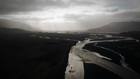 cinematic aerial thor valley, glacial rivers flowing through black volcanic floodplain, thorsmörk dramatic moody landscape iceland