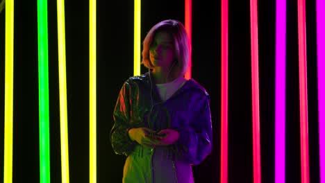 Woman in Neon Lights with Smartphone and Headphones
