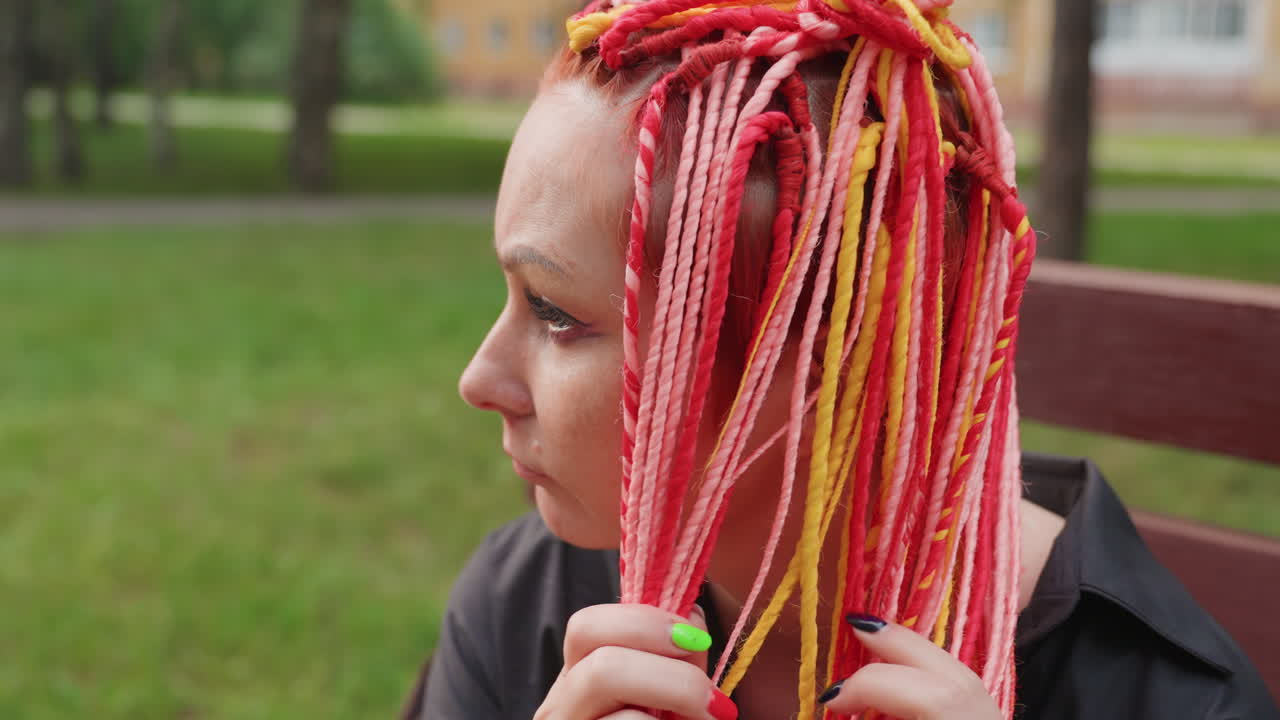 빨간 머리 여자가 조용히 야외에서 생각에 잠겨 있고, 땋은 머리를 한 차분한 여자가 평온한 공원 벤치에 앉아 있네요. 생생한 빨간색과 분홍색 땋은 머리를 한 여자가 야외에서 사색하는 모습이 부드럽게 담겨 있어요.
