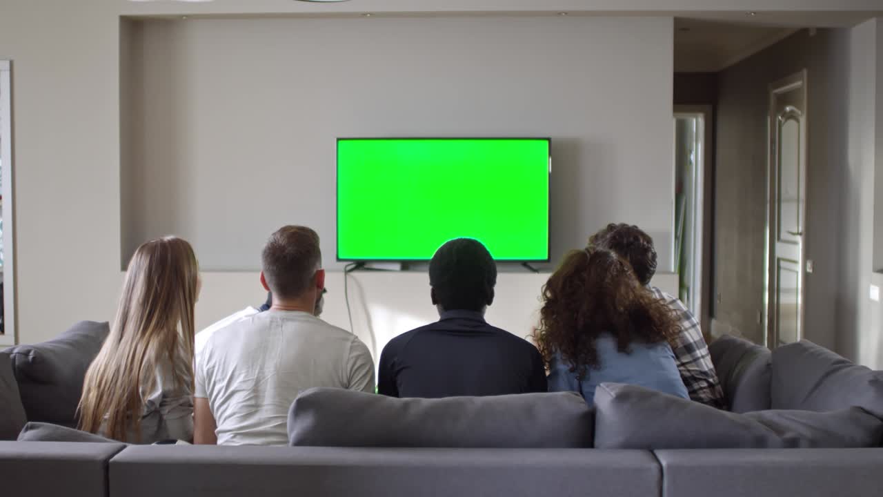 Gruppo di amici che guarda il calcio su TV Chroma Key a casa.