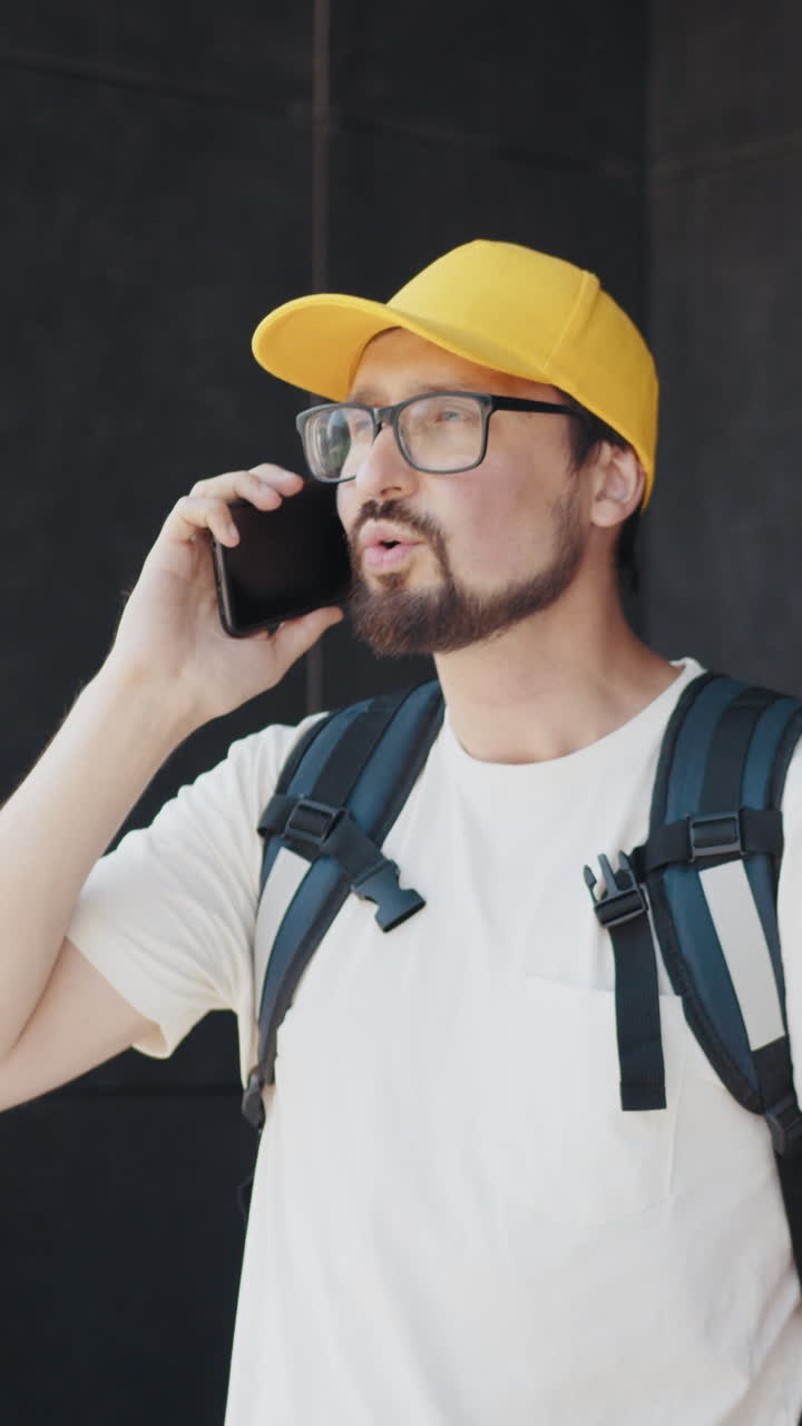 Uomo con cappello giallo che parla al telefono all'aperto