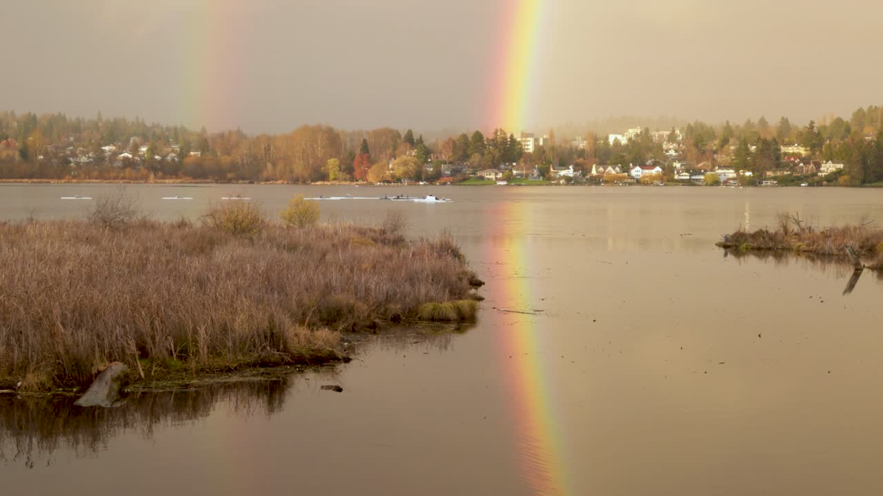 un equipo de calaveras corriendo rema a través de un brillante arco iris reflejado en la luz dorada de la tarde