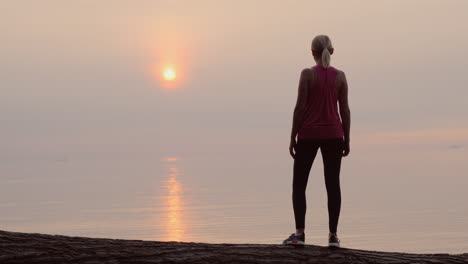 Mujer-Fitness-Segura-Mirando-El-Amanecer-Sobre-La-Vista-Trasera-Del-Mar