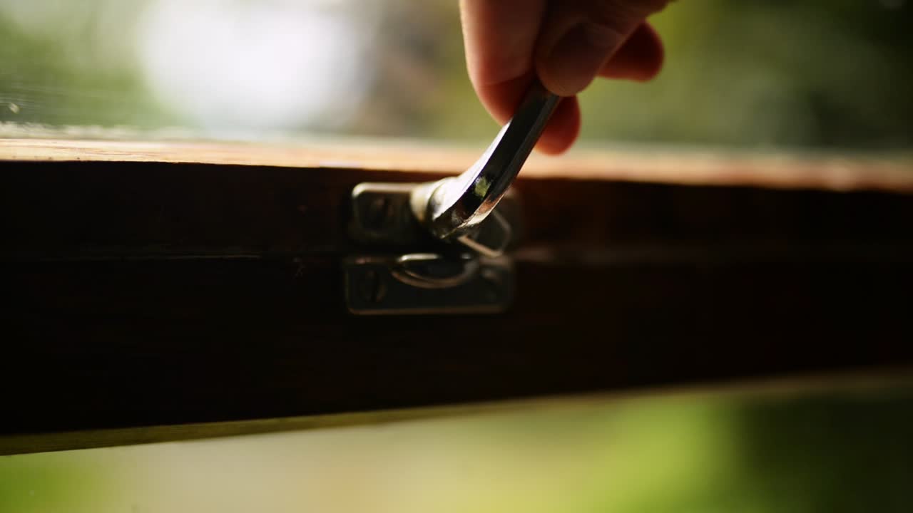 오래된 나무 창문을 손으로 닫은 다음 금속 손잡이로 잠급니다.