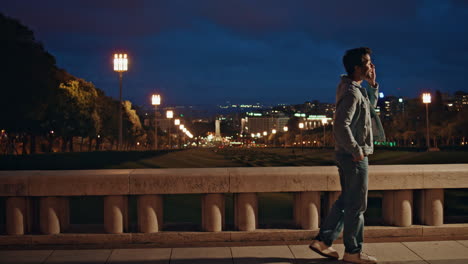 positive guy speaking mobile phone at night city view. smiling latin man talking