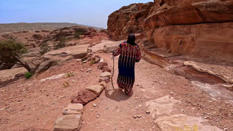 following a person in a long flowery robe walking by the ground road along the bare sandstones. scenery of a beautiful landscapes in jordan, west asia.