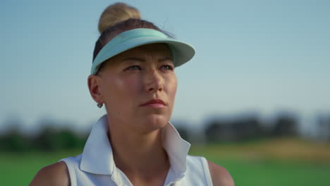 serious golfer face look away at green field. focused woman stand on golf course