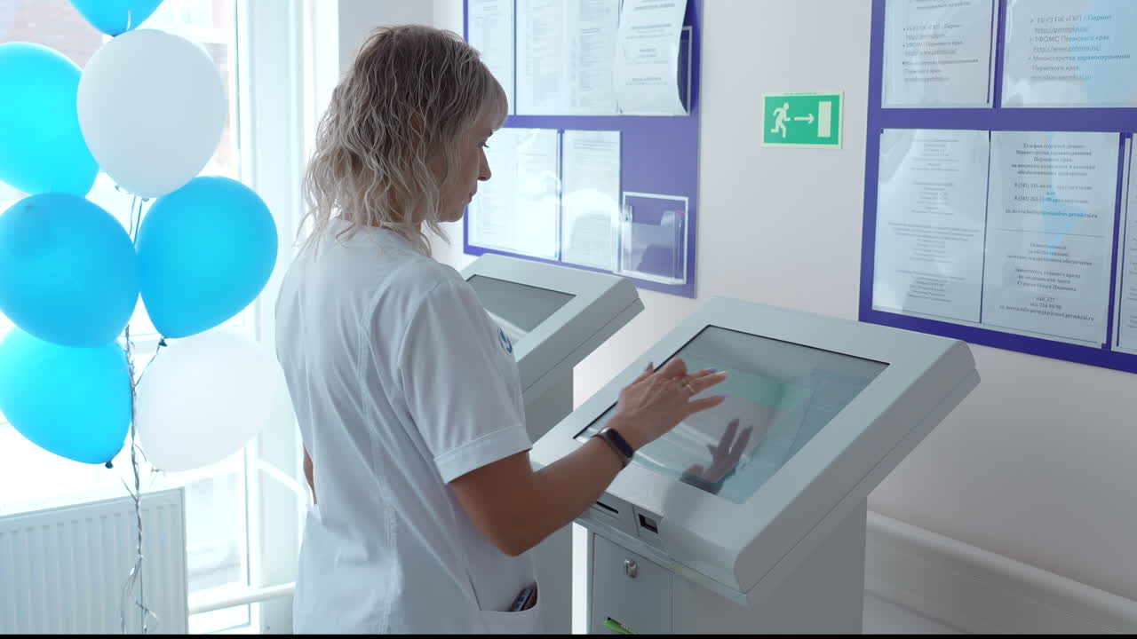 enfermera usando un quiosco de pantalla táctil en una zona de espera del hospital