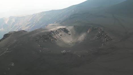 Aerial-establishing-orbit-of-volcanic-crater-cone-with-light-moving-across-from-clouds