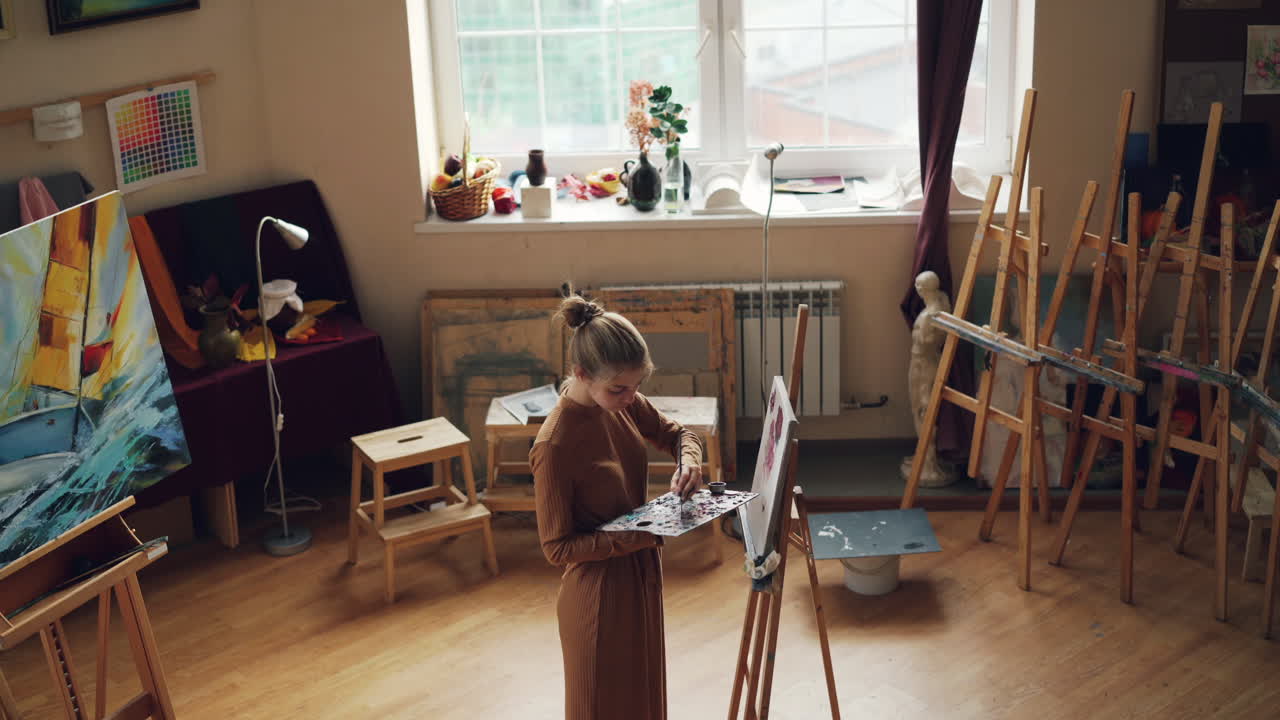 젊은 예술가가 스튜디오에서 그림을 그리고 있습니다.