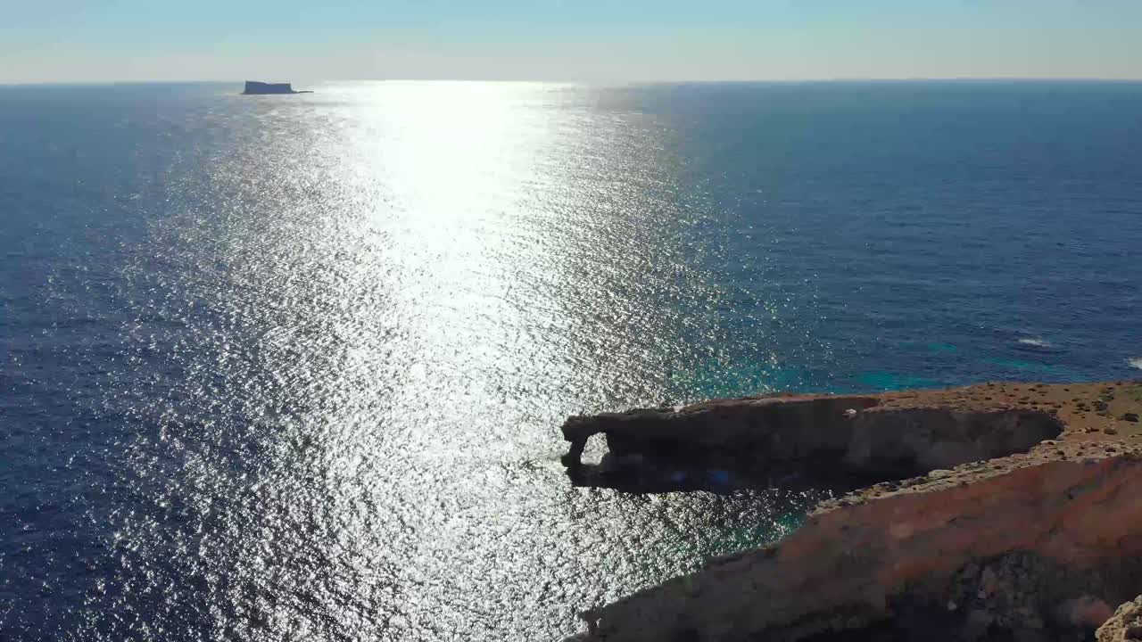 drone disparó sobre rocas en la naturaleza y hacia una ventana de piedra natural en el mar mediterráneo de malta 2