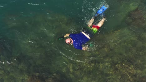 closeup aerial view above scuba snorkelling diver exploring underwater on panama coastline blue ocean coral reef