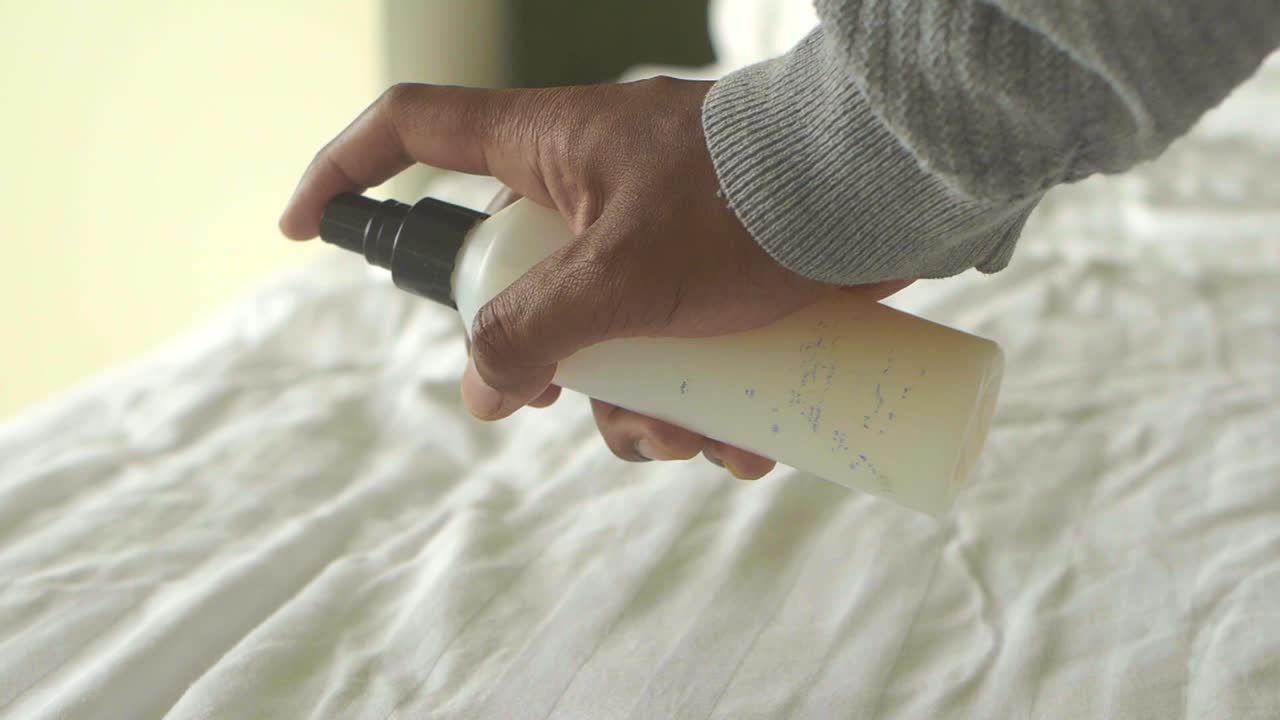Person spraying liquid on sheets
