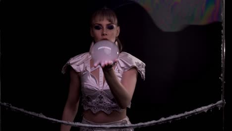 close-up: cute girl does tricks with soap bubbles. she blows a bubble from her hand towards the viewer