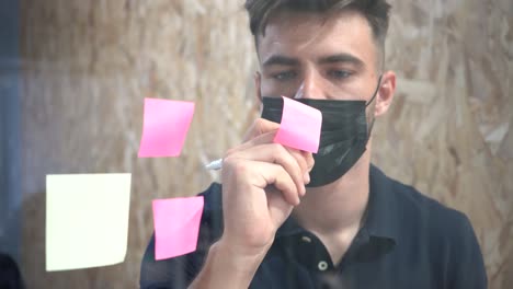 man writing on sticky note during meeting with colleagues