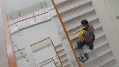 Top-View-Of-Arabic-Cleaning-Man-Wearing-Gloves-Cleaning-Stairs-With-Mop-Inside-An-Office-Building