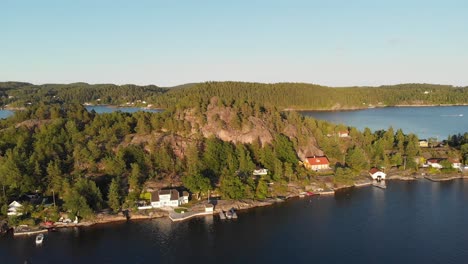 Beautiful-Norwegian-island-fishing-village-cabins-at-sunset,-aerial-panoramic