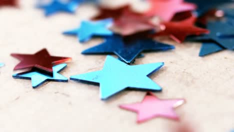 Star-shape-decorations-falling-on-wooden-table