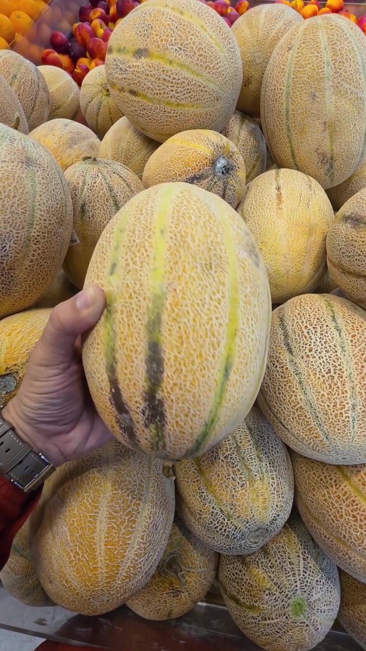 A hand holding Sweet Melon while shopping in a supermarket