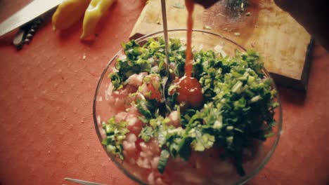 disparado desde la parte superior de las manos del chef mezclando todas las verduras con una cuchara en un cuenco