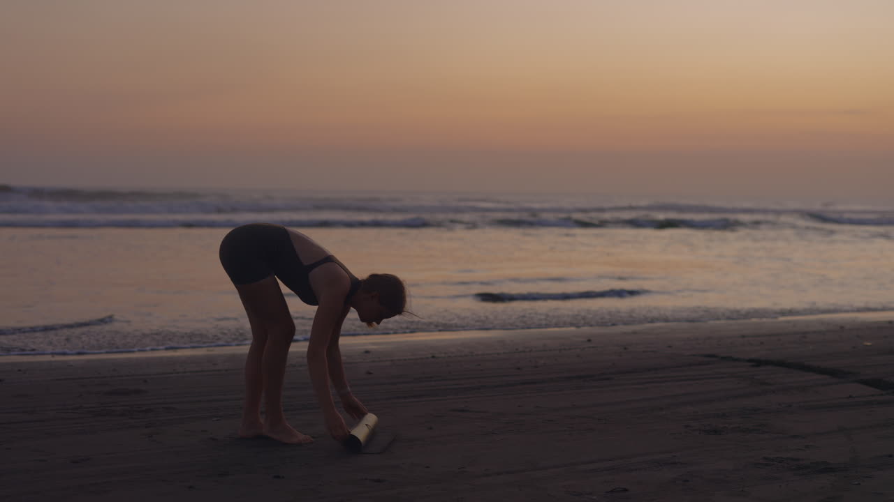 일몰 때 해변에서 요가를 하는 여자