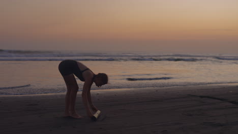 mujer haciendo yoga en la playa al atardecer