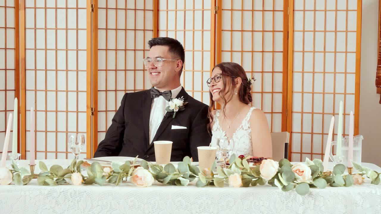 Slow-motion view of bride and groom smiling and reacting to reception speeches