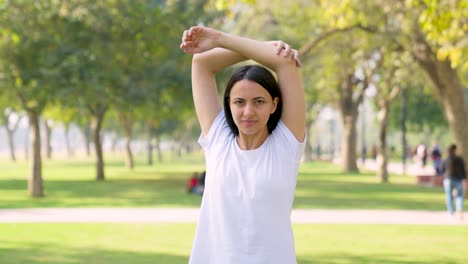 indian woman doing arm stretch in a park in morning