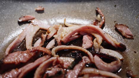 bacon strips or rashers being cooked in frying pan