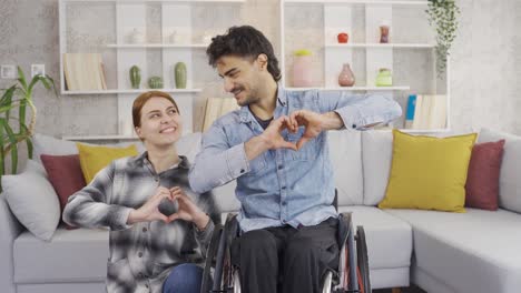 happy disabled man and his girlfriend make hearts on camera.