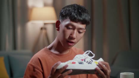 primer plano de un diseñador de zapatos asiático sonriendo a la cámara mientras trabaja en una computadora de escritorio en casa