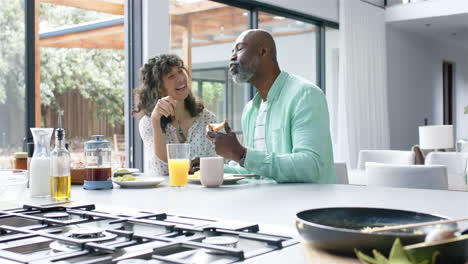 Glückliches-Biracial-Paar-Beim-Frühstück-Und-Reden-In-Der-Küche,-Zeitlupe