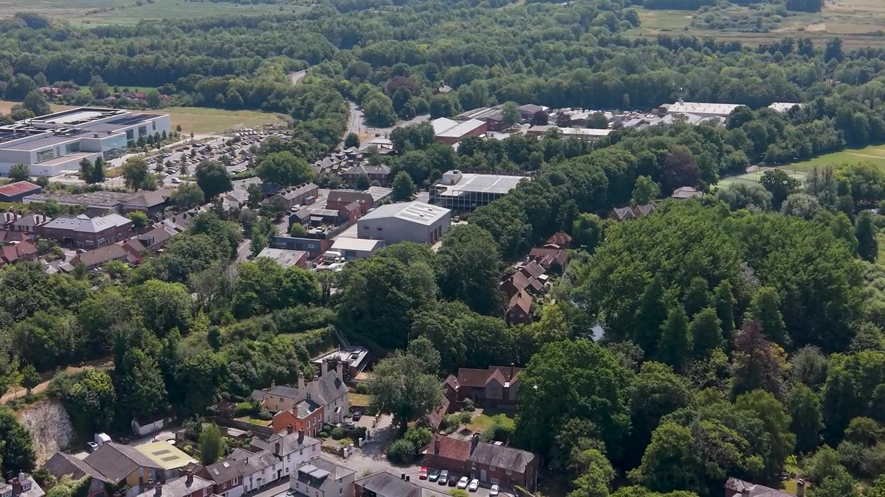 Voorwaartse luchtvlucht vertrekt vanuit het stadscentrum van Winchester en glijdt over de daken, bossen en het lichte industrieterrein van Bar End