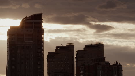 silueta de arquitectura urbana disparada por un avión no tripulado. el atardecer de la ciudad bloquea los pisos en un cielo nublado