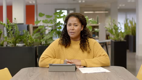 Retrato-De-Una-Mujer-De-Negocios-Birracial-Informal-En-Videollamada-En-La-Oficina,-Cámara-Lenta-Con-Espacio-Para-Copiar