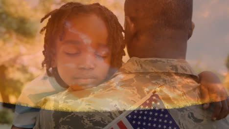 military man in uniform carrying a child holding an american flag