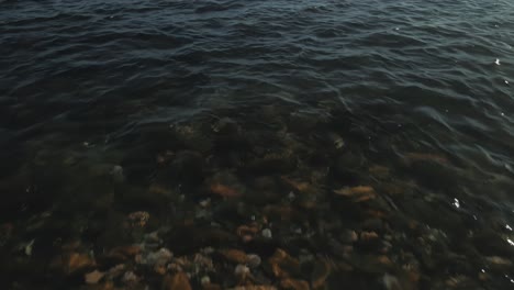 Aerial-view-of-beach-waves-moving-forward-and-tilting-up-into-the-sea-on-a-clear-day