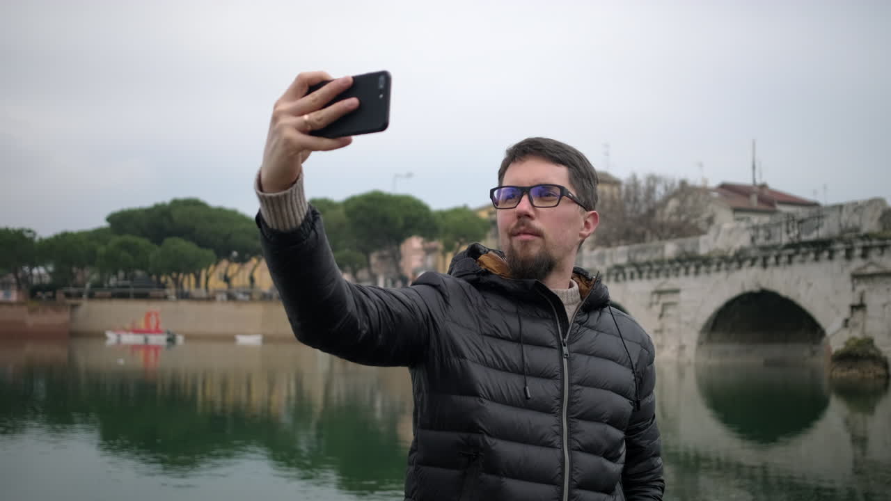Homem Tirando Selfie à Beira do Rio e da Ponte