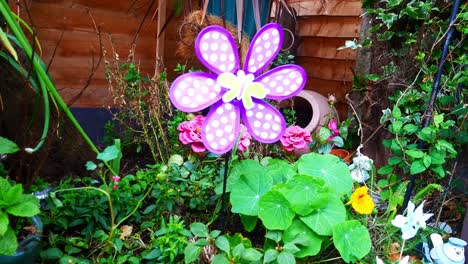 colourful spinning childlike butterfly windmill blowing in breeze among variety of blossoming flowers and plants