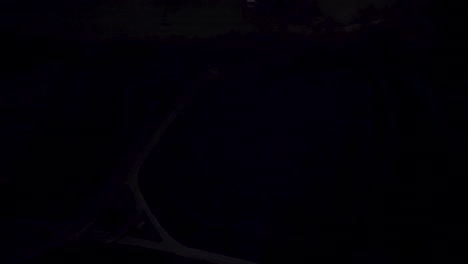 drone tilts up revealing breathtaking early morning scene: an orange-glowing sunrise, a small town shrouded in low-hanging clouds, and birds flying by