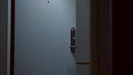 Man-with-backpack-exits-hotel-room-as-lights-turn-off,-slow-motion-close-shot
