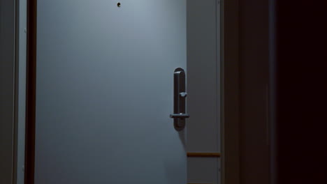 man with backpack exits hotel room as lights turn off, slow motion close shot