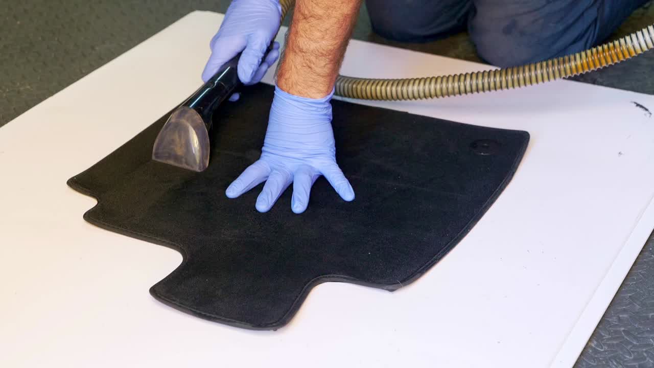 Extracting water from a small carpet car foot with a wet vac vacuum - medium shot