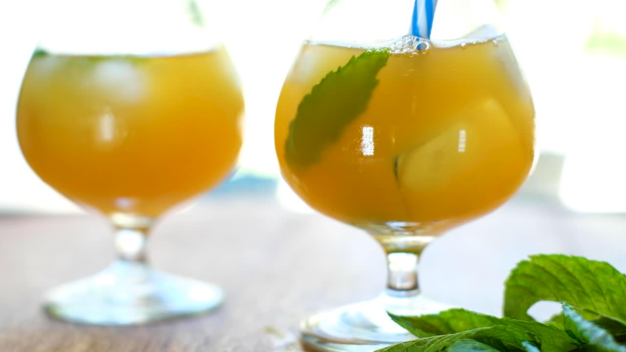 민트가 들어간 콤부차 음료와 파란색 줄무늬 빨대를 휘젓는 모습