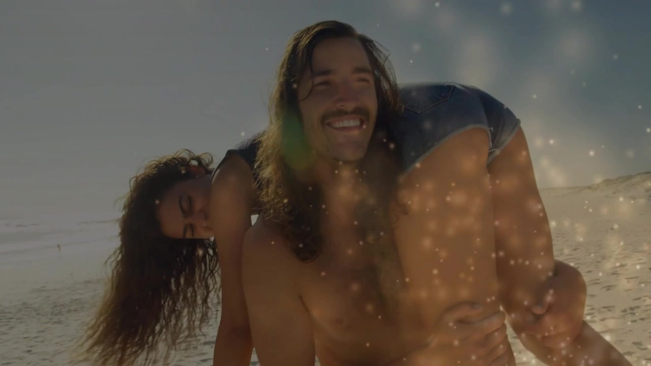 Donna che si appoggia alle spalle dell'uomo, lui la sostiene e sorride con un effetto lens flare, per contenuti di viaggio