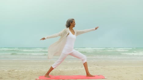 vista lateral de una mujer afroamericana senior activa haciendo ejercicio en una alfombra de ejercicio en la playa 4k