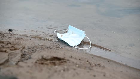 discarded surgical face mask floating on the river on a cloudy day- static shot