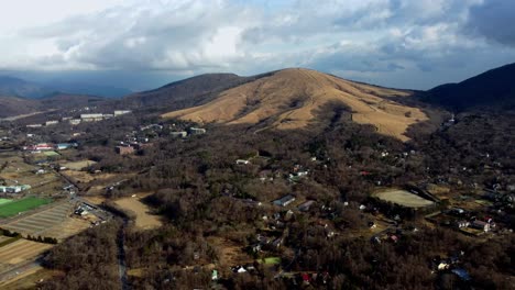 A-rural-landscape-with-houses-scattered-among-rolling-hills-and-fields,-aerial-view